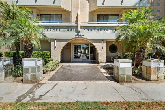 Front view of a condominium entrance with palm trees and a pathway leading to the door.