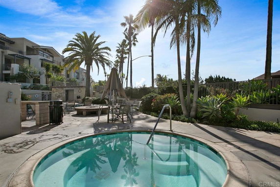 Outdoor swimming pool area with surrounding palm trees and seating.