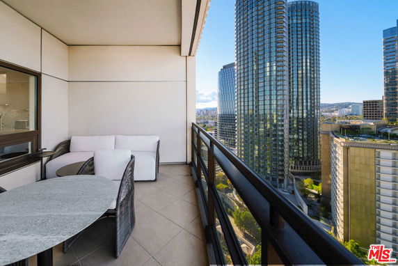 Balcony with furniture overlooking cityscape and tall buildings