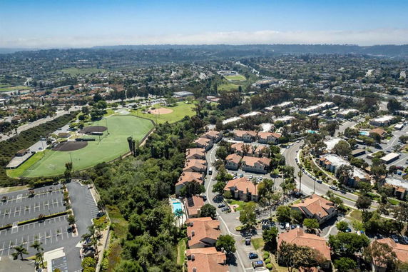 Panoramic aerial view of a residential area with adjacent sports fields and parking lot.