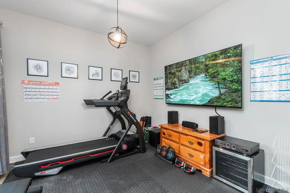 Indoor gym area with a treadmill, TV, and weights.