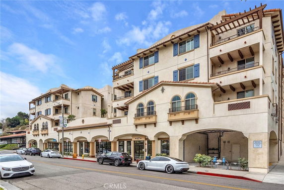 Front view of a multi-story Mediterranean-style building with balconies and arches.