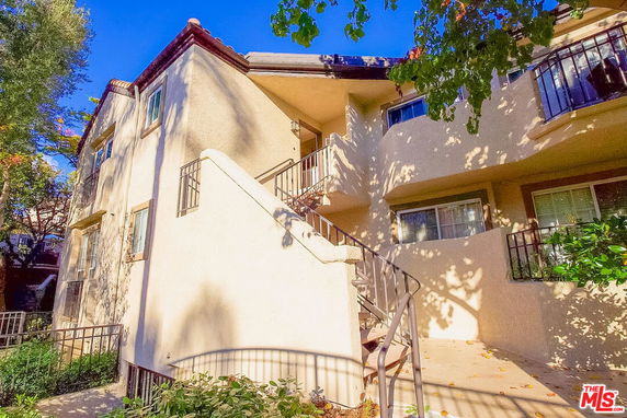 Front view of a multi-story residential building with balconies and an outdoor staircase.