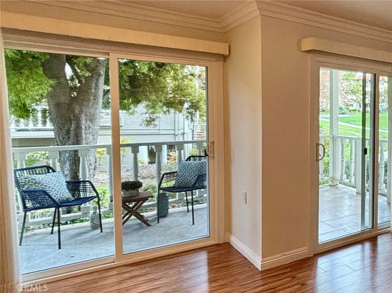 View of outdoor seating area with chairs and trees through sliding glass doors.