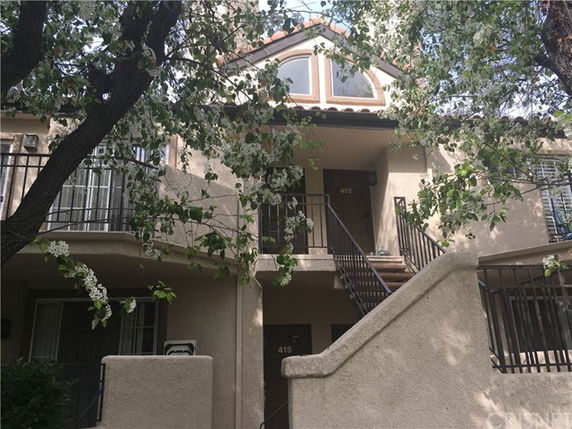 Front view of a two-story residential building with balconies and an external staircase.