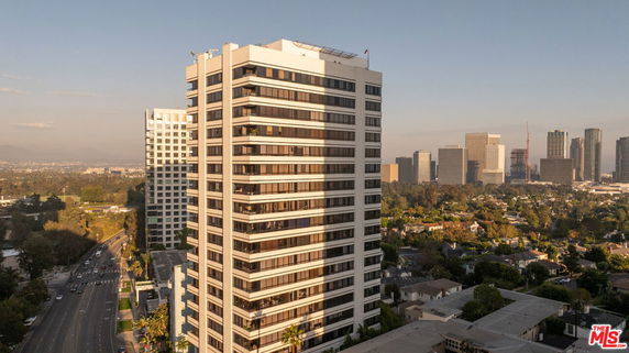 Front view of a tall, modern, multi-story building with glass windows.
