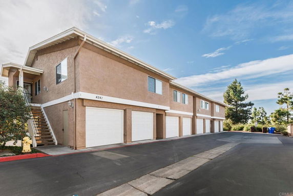 Front view of a multi-unit residential building with garages and an external staircase.