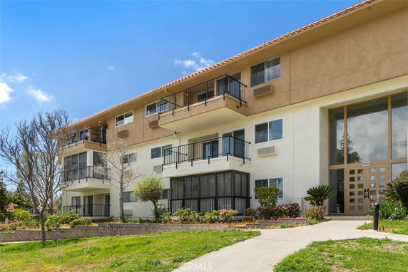 Front view of a multi-story apartment building with balconies and large entrance.