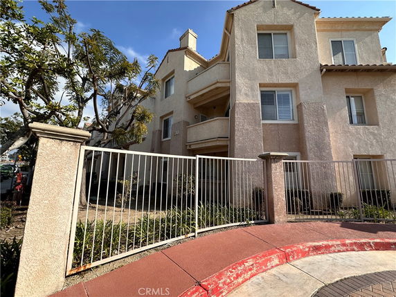 Front view of a multi-story residential building with a fence and balcony.