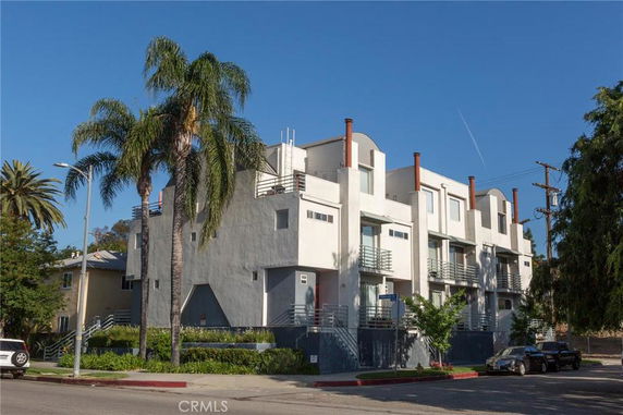 Front view of a modern multi-story building with balconies and large windows.