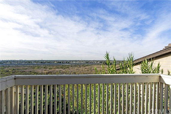 Panoramic view from a balcony overlooking a natural landscape and distant buildings.