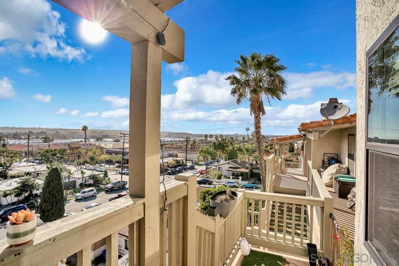 View of surrounding area from a building with balconies and palm trees.