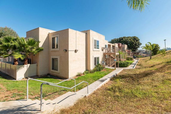 Side view of a two-story apartment building with balconies and a walkway.