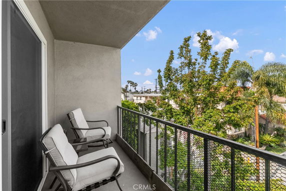 Balcony view with trees and neighboring buildings.