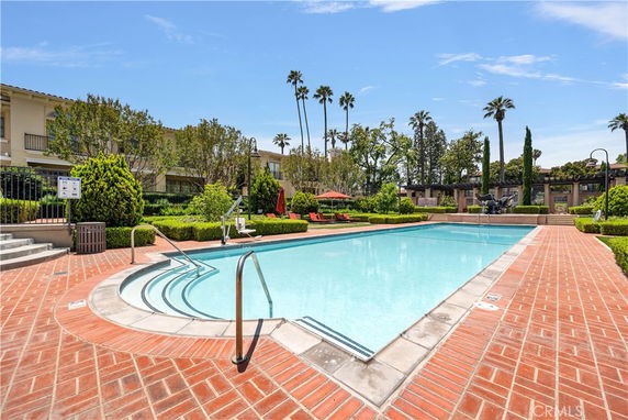 Outdoor swimming pool surrounded by brick paving and greenery.