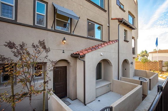 Front view of a multi-story house with arched entrances and a brown door.