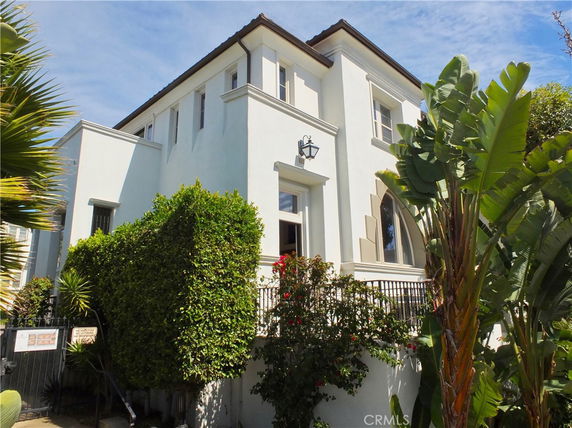 Front view of a multi-story house with a white exterior and multiple windows.