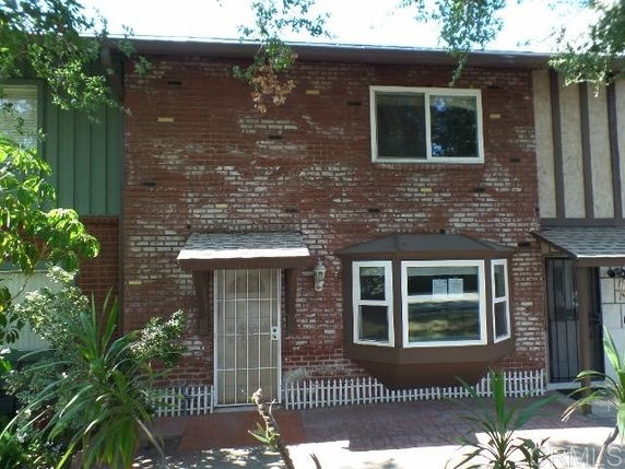 Front view of a two-story brick house with a bay window and security door.