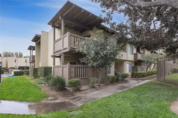 Front view of a multi-story residential building with balconies and surrounding greenery.