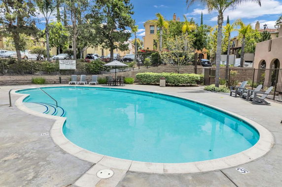 Outdoor swimming pool area with lounge chairs and patio furniture.