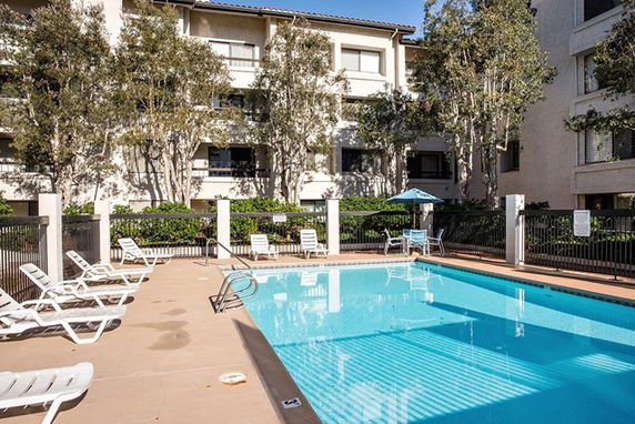 Outdoor swimming pool area with lounge chairs and surrounding buildings.