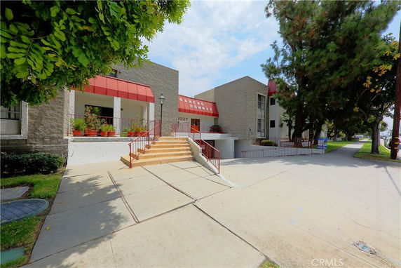 Front view of a building with stairs and red awnings.