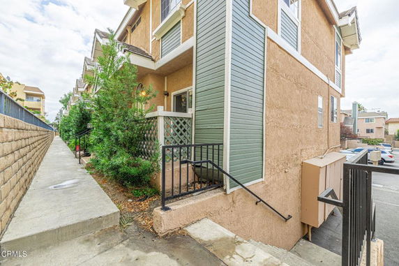 Side view of a multi-story townhouse with a small porch and walkway.