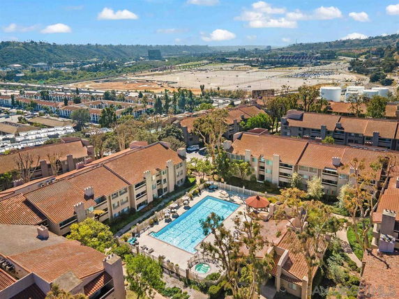 Aerial view of a residential complex with a central swimming pool and surrounding buildings.