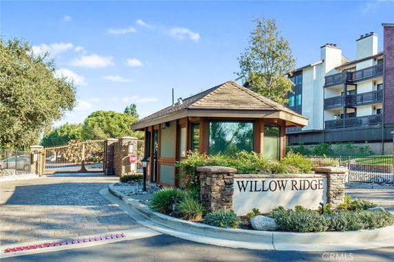 Front view of a gated community entrance with a small building and sign reading 'Willow Ridge.'