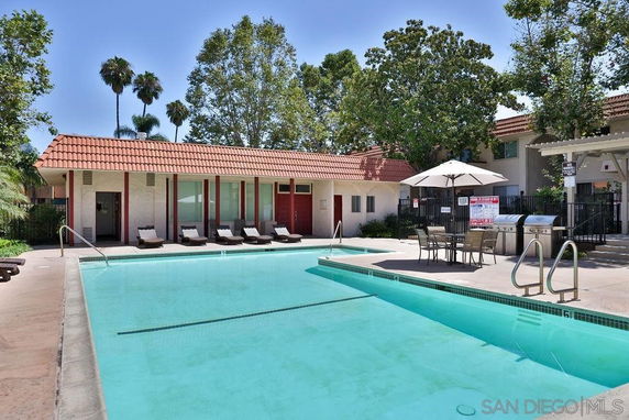 Outdoor swimming pool area with lounge chairs and an umbrella.