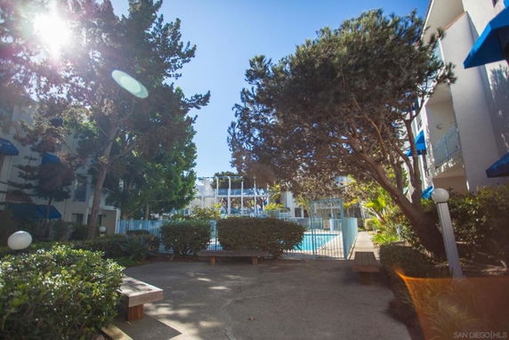 Swimming pool area surrounded by residential buildings and trees.