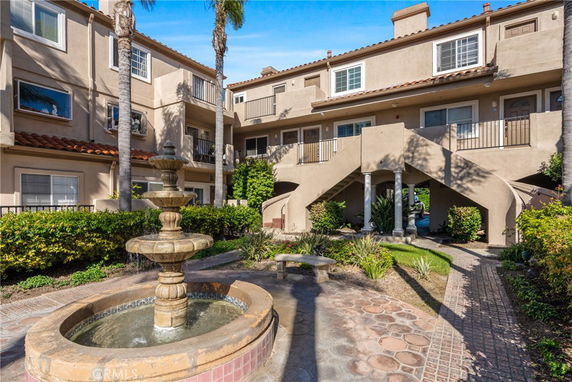 Front view of a multi-story building with staircases and a fountain in the foreground.