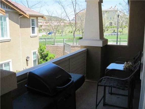 View from a balcony showing neighboring buildings and a grassy area.