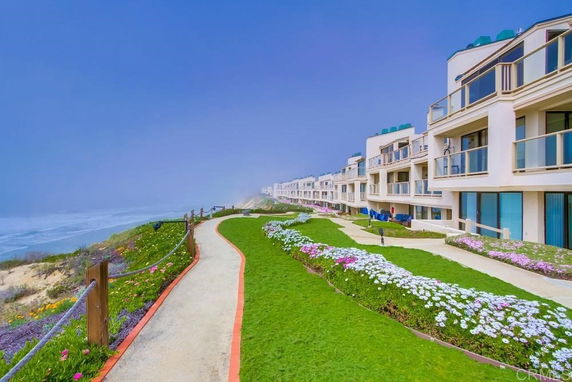 Front view of oceanfront apartments with balconies and glass railings.
