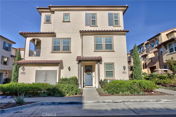 Front view of a multi-story house with a garage and a balcony.