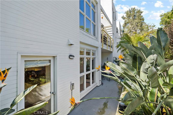 View of a house exterior with large windows and a small patio area.