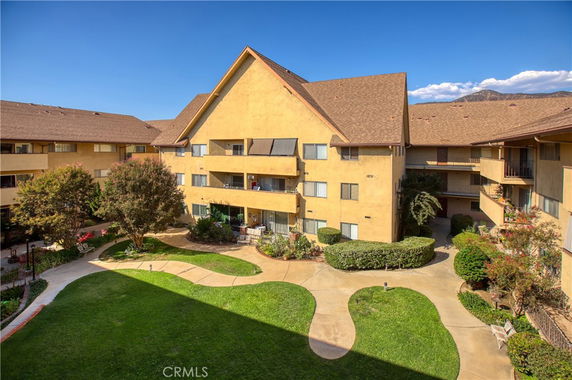 View of multi-story apartment building with courtyard and paths.