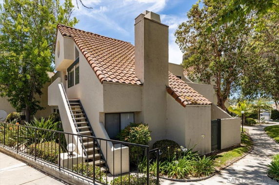 Front view of a multi-level building with stairs leading to the entrance and a sloped tile roof.