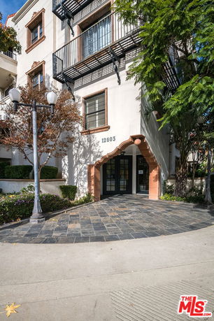 Front view of a multi-story building entrance with a distinct arched doorway and balconies.