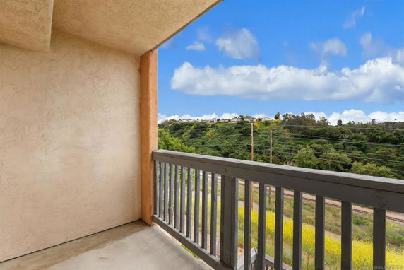 View from a balcony showing a scenic landscape with greenery and a clear sky.