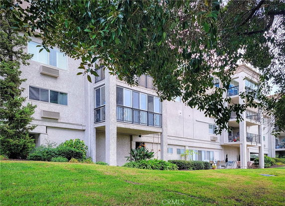 Front view of a multi-story apartment building with balconies and large windows.