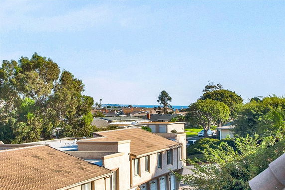 View of residential buildings and trees with the ocean in the distance.