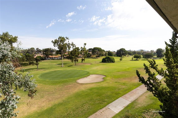 Wide view of a golf course with lush green grass and trees.