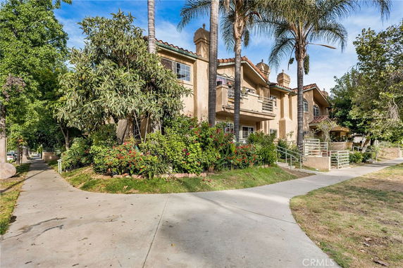 Front view of a multi-story house with balconies and surrounding vegetation.