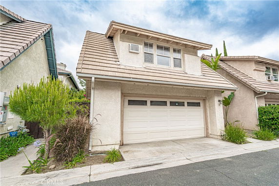 Front view of a two-story house with a white garage door and pitched roof.