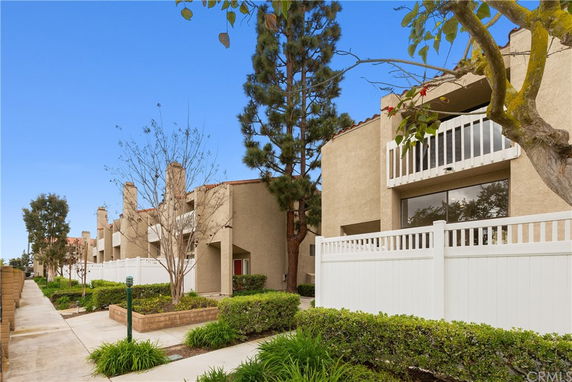 Front view of a multi-story building with balconies and white fencing.