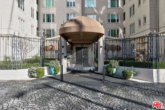 Front view of a multi-story building with a gated entrance and decorative canopy.