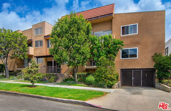 Front view of a three-story apartment building with a tiled roof and garage entry.