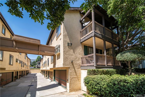 Front view of a multi-story residential building with balconies and a connecting walkway.