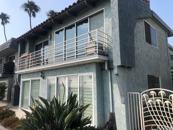Front view of a two-story house with balcony and large windows.